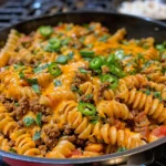 Cheesy taco pasta dish topped with cheese and fresh ingredients.